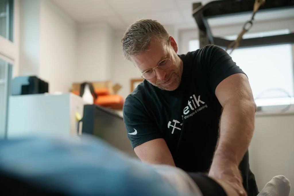 Sebastian Kaul von x-thletik führt eine manuelle Behandlung am Bein eines Patienten durch. Das Bild vermittelt den persönlichen und gezielten Charakter manueller Therapie zur Linderung von Beschwerden und zur Förderung der Mobilität.