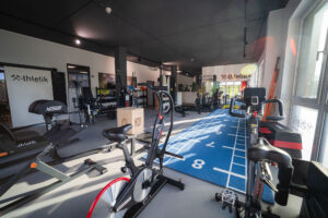 Modern ausgestattetes Fitnessstudio von x-thletik mit verschiedenen Trainingsgeräten, Sprintstrecke und funktionellen Bereichen – Symbol für personalisiertes Training und individuelle Betreuung zum Weltgesundheitstag.